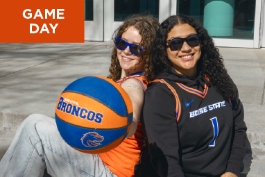 Mobile Game Day image with a 2 students in basketball jersyes with a orange and blue basketball in hand. Tap to shop Game Day gear.